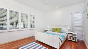 Dormitorio blanco con cama y ventanas en Tranquil Beachside Escape, en Killcare