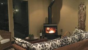 a fireplace in a living room with a couch with a fire at Wirreanda Retreat Acreage in Macmasters Beach