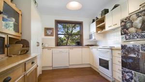 a kitchen with white cabinets and a window at 'Charming Cottage Retreat' by HolidayCo in Killcare