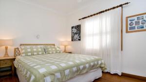 a white bedroom with a bed and a window at 'Charming Cottage Retreat' by HolidayCo in Killcare