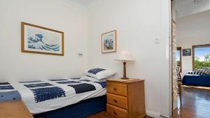 a bedroom with a bed and a dresser with a lamp at 'Charming Cottage Retreat' by HolidayCo in Killcare +4 photos