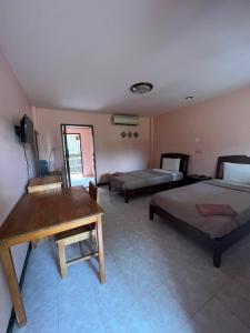 - une chambre avec 2 lits, un bureau et une table dans l'établissement Sawai Home Resort, à Nathon