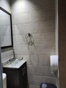 y baño con ducha y pared de azulejos. en Hostal Machu Picchu Medellín, en Medellín
