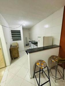 cocina con 2 sillas, barra y nevera en Apartamento Espaçoso, Mobiliado 02 Dormitórios Zn Ap 03 en São Paulo