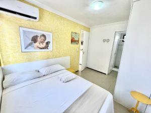a bedroom with a white bed with a picture on the wall at Alessandra Residence | Meireles - CE in Fortaleza