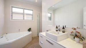 een witte badkamer met een bad en een wastafel bij Splendour On Grandview in Killcare