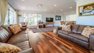 a living room with a leather couch and a television at 'Spacious Family Retreat' by HolidayCo in Killcare