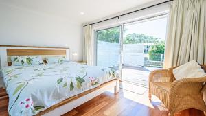 a bedroom with a bed and a window and a chair at 'Spacious Family Retreat' by HolidayCo in Killcare