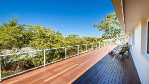 a balcony with a wooden deck with benches on it at 'Spacious Family Retreat' by HolidayCo in Killcare