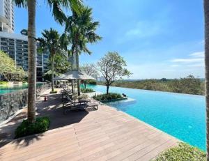 a pool with benches and an umbrella next to a building at Classical Cozy Iskandar Residence 3BR nr Legoland by Our Stay in Nusajaya