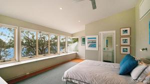 Schlafzimmer mit einem Bett und großen Fenstern in der Unterkunft Stylish Haven At Pretty Beach - Wifi in Pretty Beach