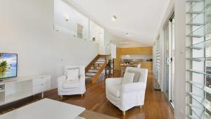 un salon avec deux chaises blanches et un escalier dans l'établissement 'Belvidere Cottage' by HolidayCo, à Pretty Beach