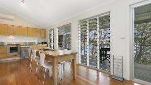 une cuisine avec une table et des chaises en bois dans l'établissement 'Belvidere Cottage' by HolidayCo, à Pretty Beach