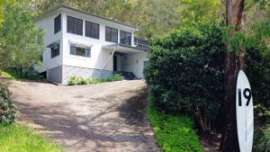 una casa blanca con una entrada delante de ella en 'Space and Serenity at Pretty Beach' by Accom Holidays, en Pretty Beach