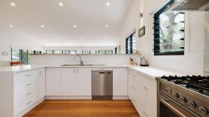 Una cocina blanca con fregadero y estufa. en 'Space and Serenity at Pretty Beach' by Accom Holidays, en Pretty Beach