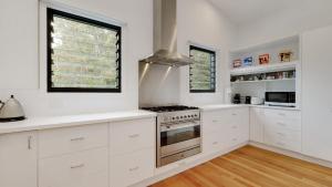 Una cocina con gabinetes blancos y una estufa. en 'Space and Serenity at Pretty Beach' by Accom Holidays, en Pretty Beach