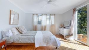 ein weißes Schlafzimmer mit einem Bett und einem Fenster in der Unterkunft Bouddi Beach Retreat in Killcare
