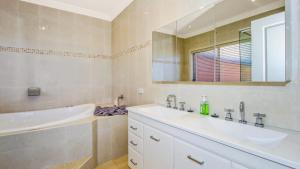 a bathroom with two sinks and a tub and a mirror at 'Gone Coastal' by HolidayCo in Killcare