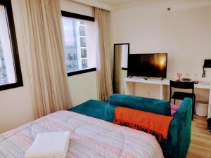 a bedroom with a bed and a couch and a television at The Best Urban Deluxe - Duplex Studio - Hotel QLTY Faria Lima - by LuXXoR in Sao Paulo