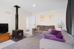 a living room with a couch and a stove at Rose Cottage - Lake Coleridge Holiday Home in Lake Coleridge