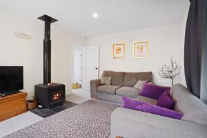 ein Wohnzimmer mit einem Sofa und einem Herd in der Unterkunft Rose Cottage - Lake Coleridge Holiday Home in Lake Coleridge