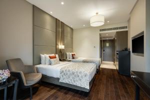 a hotel room with two beds and a chair at Palm Meadows Resort in Bangalore