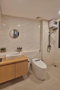 a white bathroom with a toilet and a sink at Yama Onsen Villa in Bandung