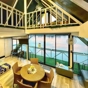 Habitación con mesa, sillas y ventana grande. en แพรุ่งธารา ไชโย (Rungtara Houseboats) 