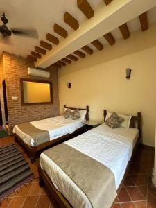 um quarto com 2 camas e uma parede com um espelho em River Park International Resort em Chitwan