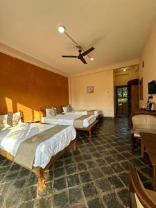 Habitación de hotel con 3 camas y ventilador de techo. en River Park International Resort en Chitwan