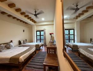 a bedroom with three beds and a mirror at River Park International Resort in Chitwan