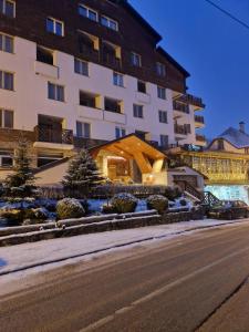 a large building with snow on the ground next to a street at FOKA SPA APARTMANI 30 m from Junior in Brzeće