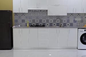 cocina con armarios blancos y nevera negra en Lavender seenu feydhoo addu city, en Feydhoo