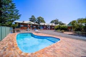 a swimming pool in a brick yard with a fence at Golf Place Inn Wollongong in Primbee