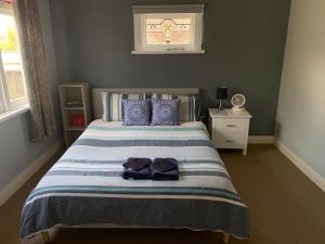 a bedroom with a bed with blue and white stripes at RS Two-Bedroom Apartment in Palmerston North