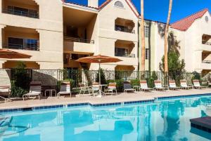 a swimming pool with chairs and umbrellas next to a building at Amazing Deluxe 1-Bedroom - Next to Sphere in Las Vegas! in Las Vegas