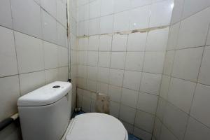 a dirty bathroom with a toilet and tiled walls at OYO 93429 Pondok Surya in Pakato