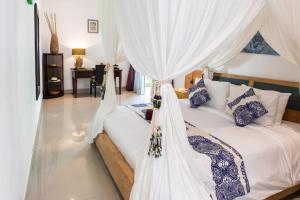 a bedroom with a bed with white curtains at MasBro ART Villas in Seminyak