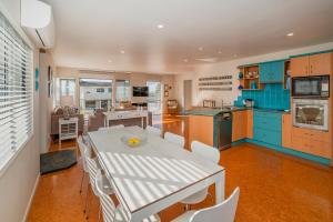 a kitchen with blue cabinets and a white table and chairs at Beach View Bliss - Pauanui Holiday Home in Pauanui