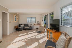a living room with a television and a couch at Beach View Bliss - Pauanui Holiday Home in Pauanui