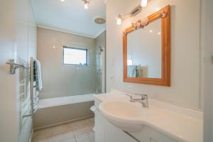 a white bathroom with a sink and a mirror at Beach View Bliss - Pauanui Holiday Home in Pauanui +21 photos