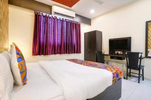 KolshetにあるFabHotel Sai Viharのベッドとテレビが備わるホテルルームです。