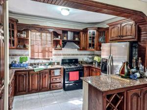 a kitchen with wooden cabinets and a stove top oven at La Romana Vacation Home in Cumayasa Kilómetros 4 1/2