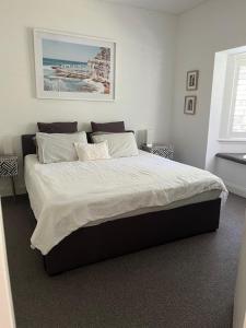 um quarto com uma cama grande e lençóis brancos em Modern Queens Park Home near Bondi Junction, Bondi Beach & City em Sydney