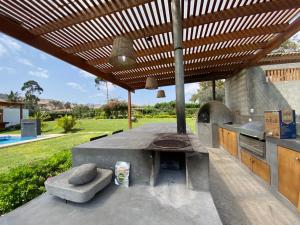 una cocina al aire libre con horno al aire libre y techo de madera en Casa de campo con piscina, en Miraflores