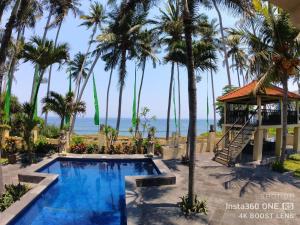 a swimming pool with palm trees and a beach at Jasri Ombak in Karangasem