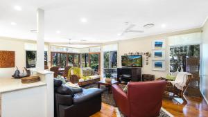 a living room with leather chairs and a television at Waters Edge - Pet Friendly Holiday Home in Pearl Beach
