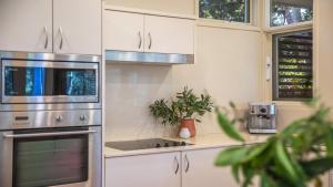 a kitchen with white cabinets and a stainless steel appliance at Waters Edge - Pet Friendly Holiday Home in Pearl Beach