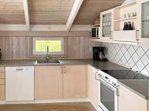 Two-Bedroom Holiday home in Hjørring 1 في لونستروب: مطبخ مع دواليب بيضاء ومغسلة