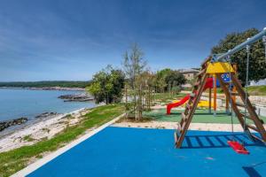 a playground with a slide next to the water at Apartment Rajka - 20m from beach in Koromačno